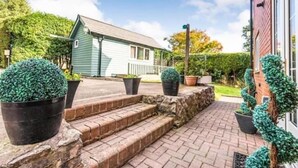 A house with a brick pathway leading to a front door, surrounded by potted plants and a well-maintained lawn.