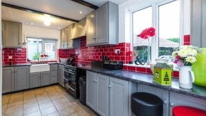 A modern kitchen with grey cabinets, red-tiled backsplash, and a window with a view of greenery.