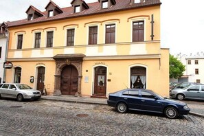 A two-story building with a yellow facade, a large wooden door, and the number 32 on the ground floor.