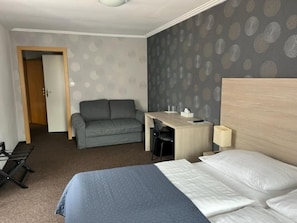 Een hotelkamer met een bed, een bureau, een stoel, een bank en een deur.