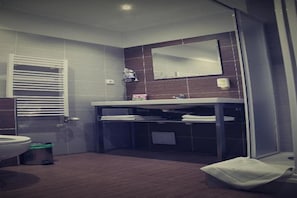 Een moderne badkamer met toilet, wastafel, spiegel en handdoekhouder.