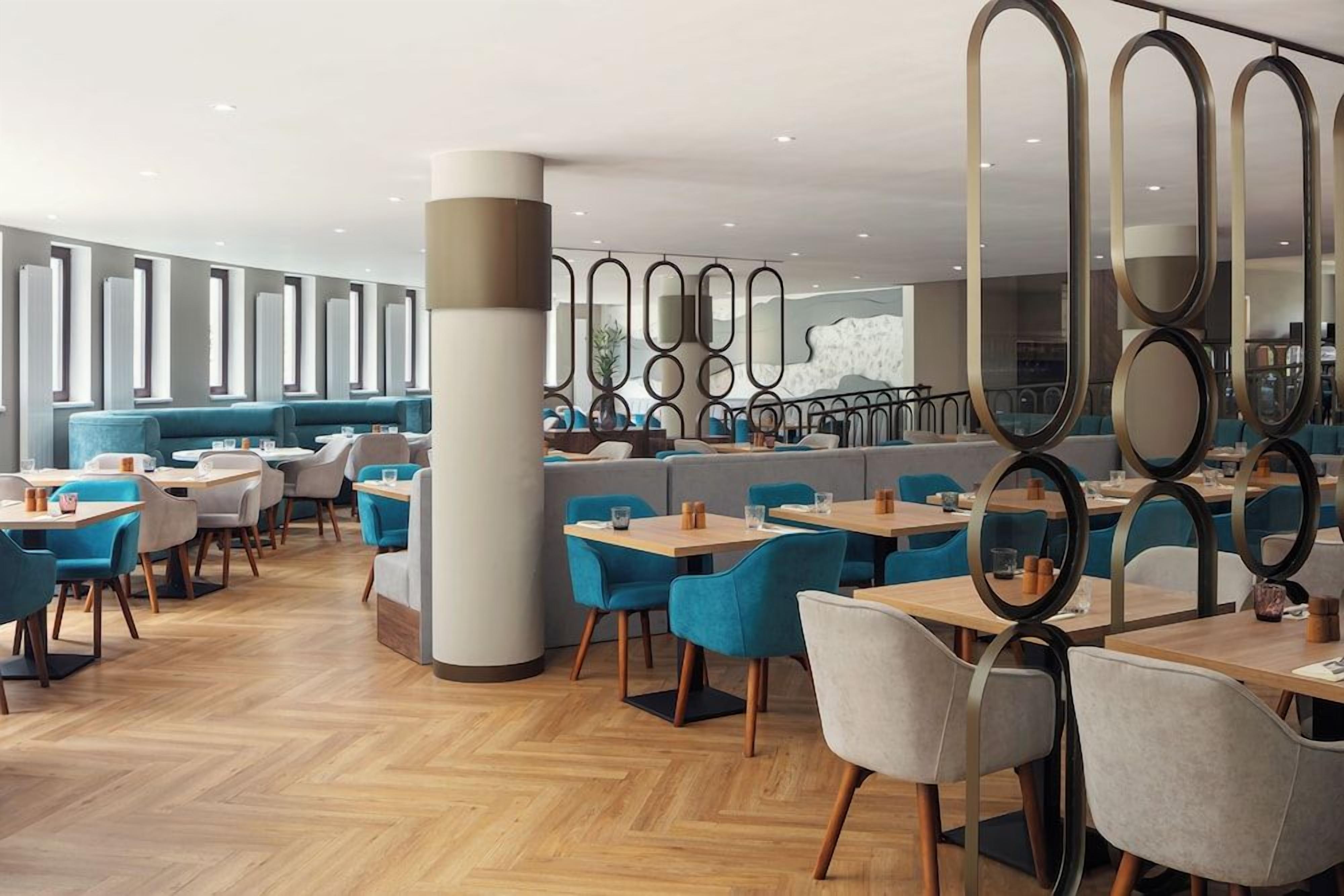 A modern restaurant interior with seating arrangements, tables, and decorative mirrors.