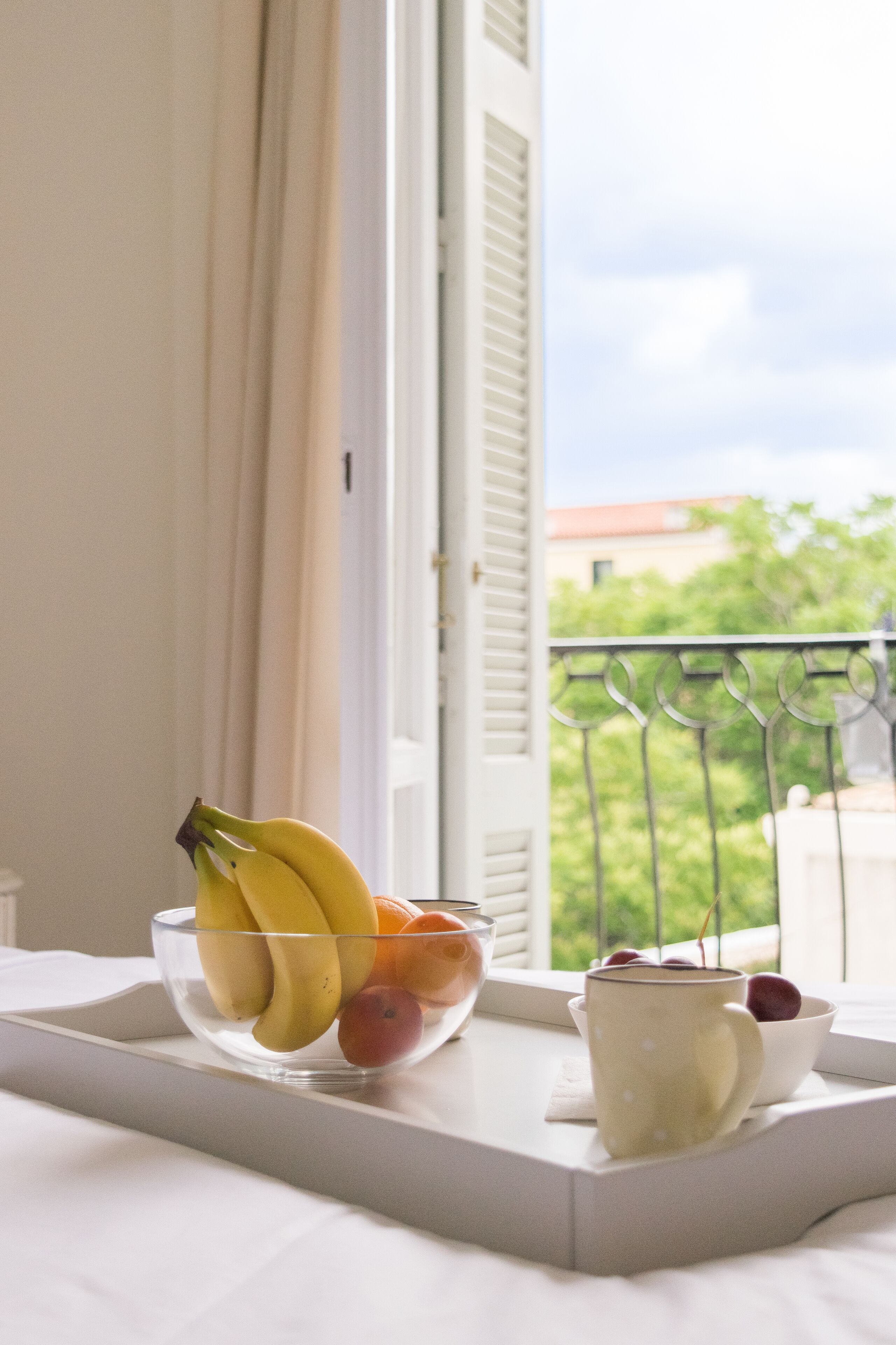 Un plateau avec un saladier de fruits et une tasse sur un balcon.