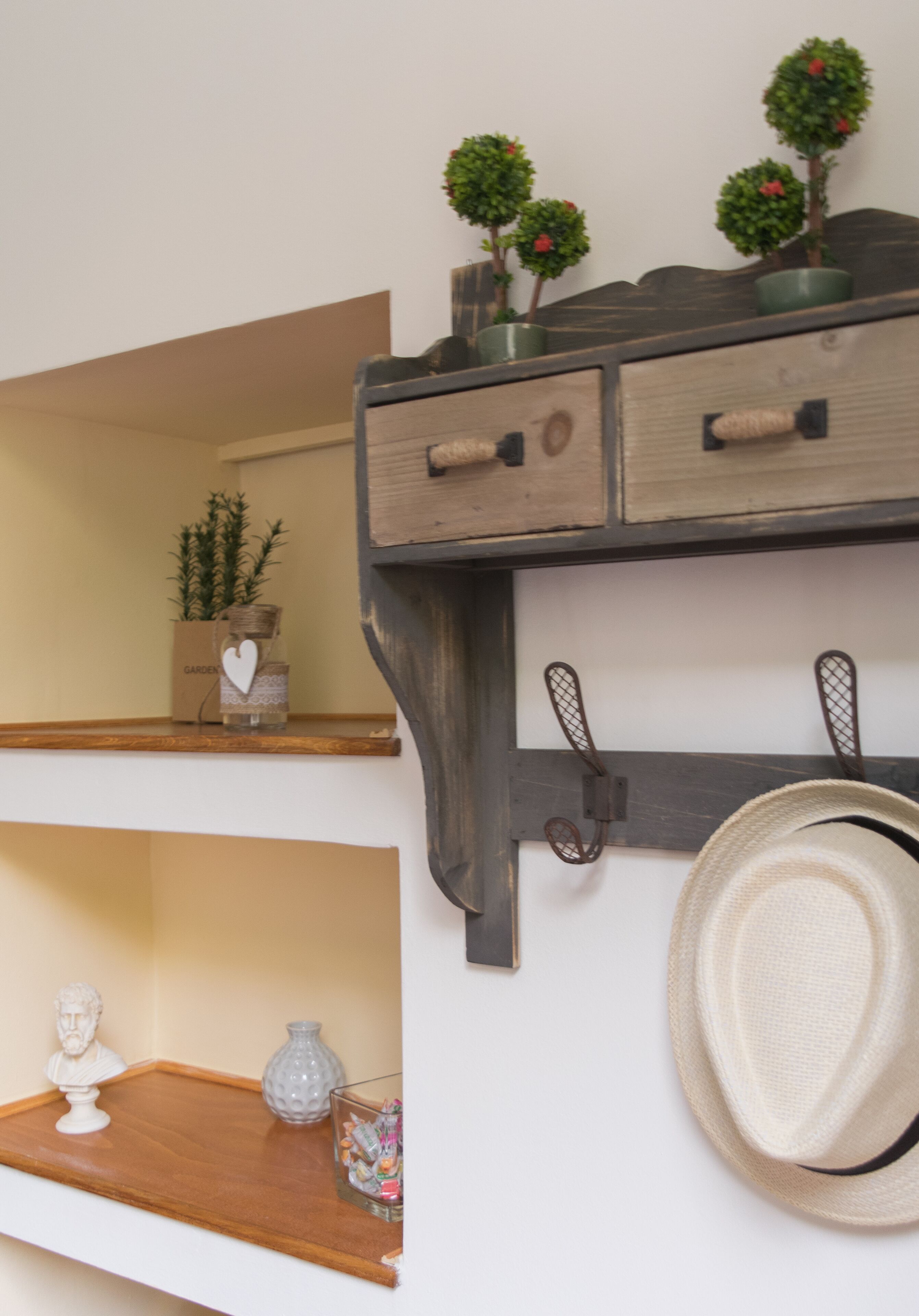 A wooden shelf with decorative items, a hat, and a small bust.