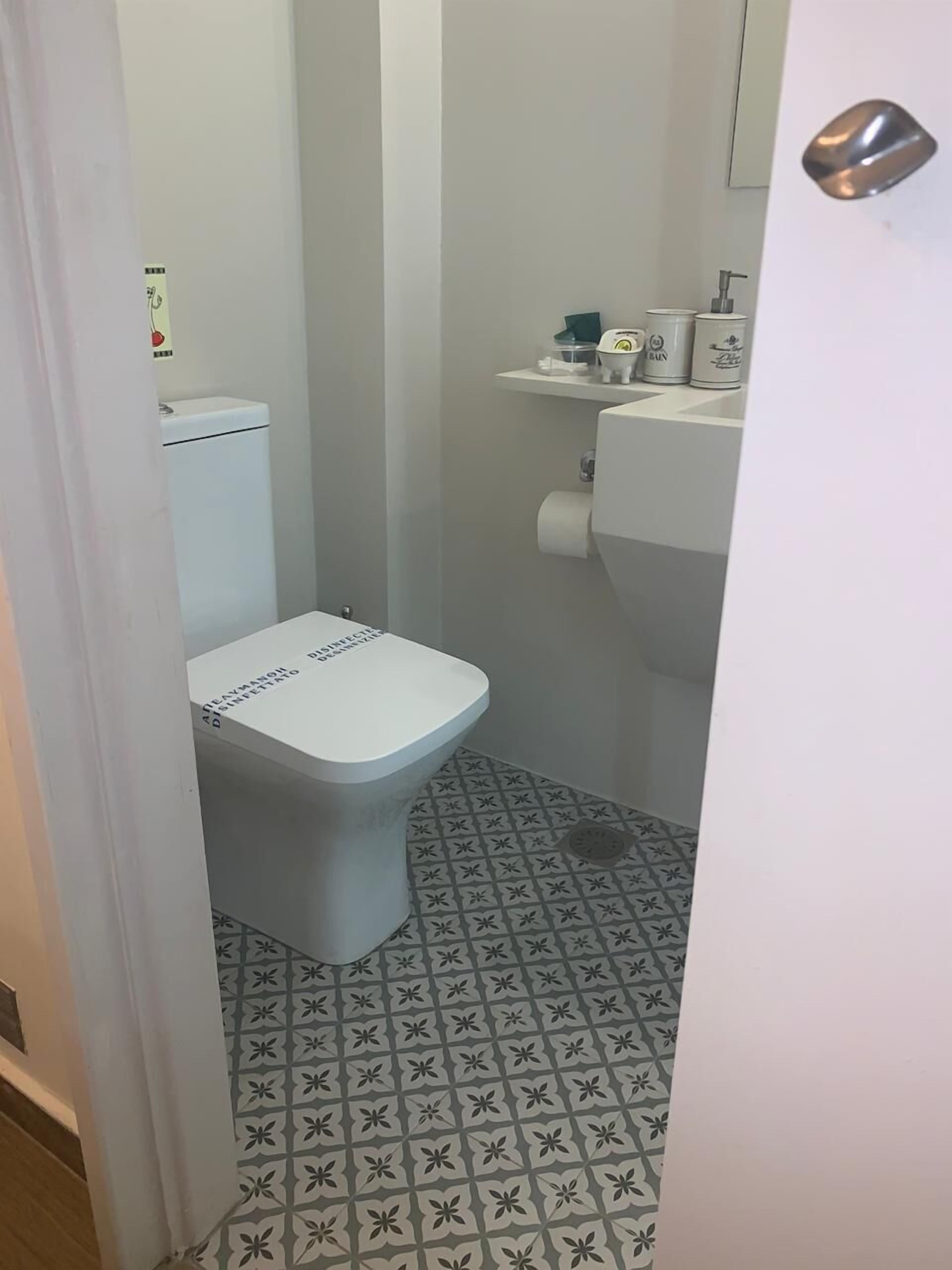 Ein kleines Badezimmer mit Toilette, Waschbecken und Toilettenpapierhalter.