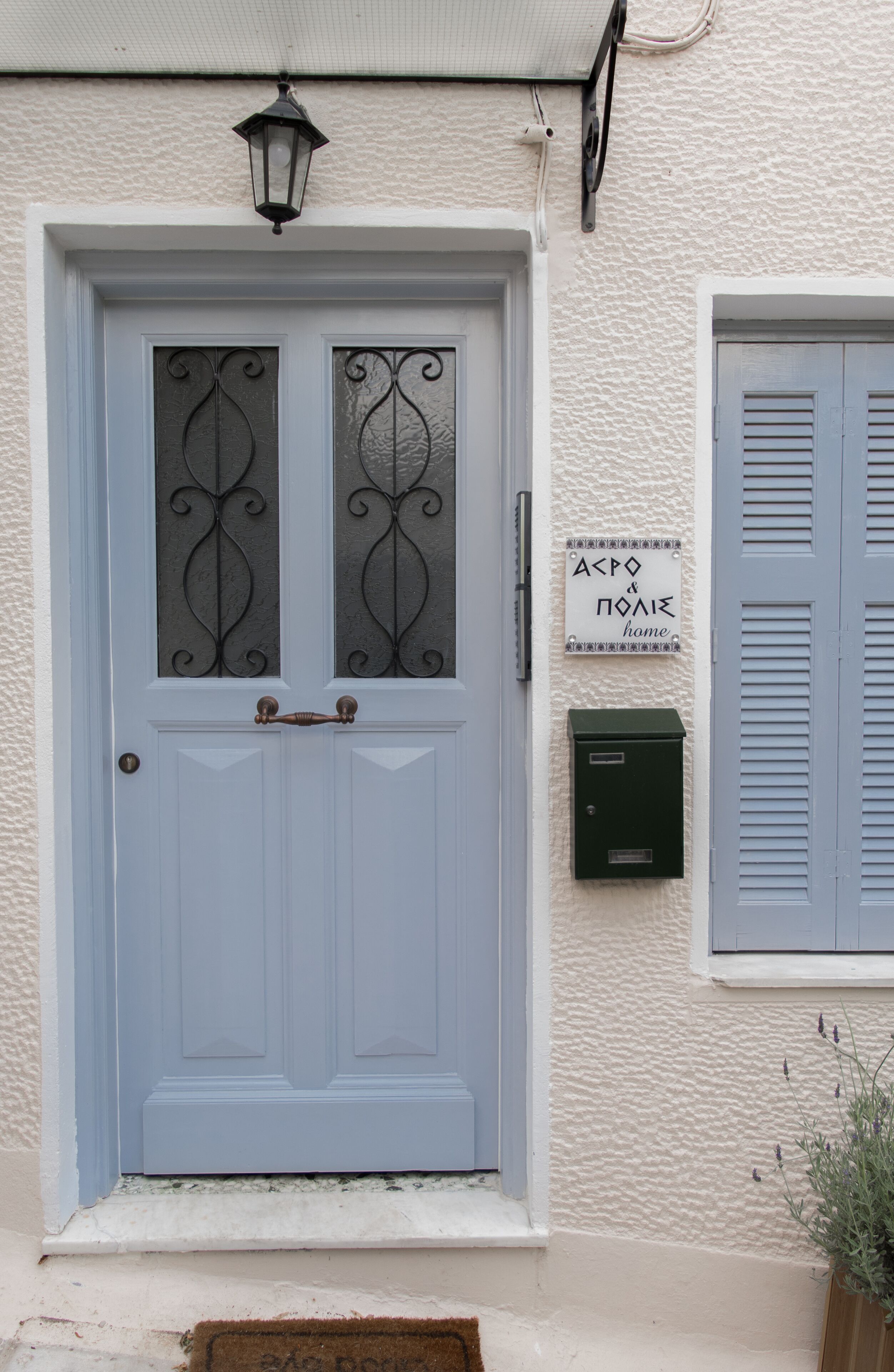 A light blue door with decorative glass panels, a small outdoor light fixture above, and a sign reading "APPO & PONIE home" on the wall.