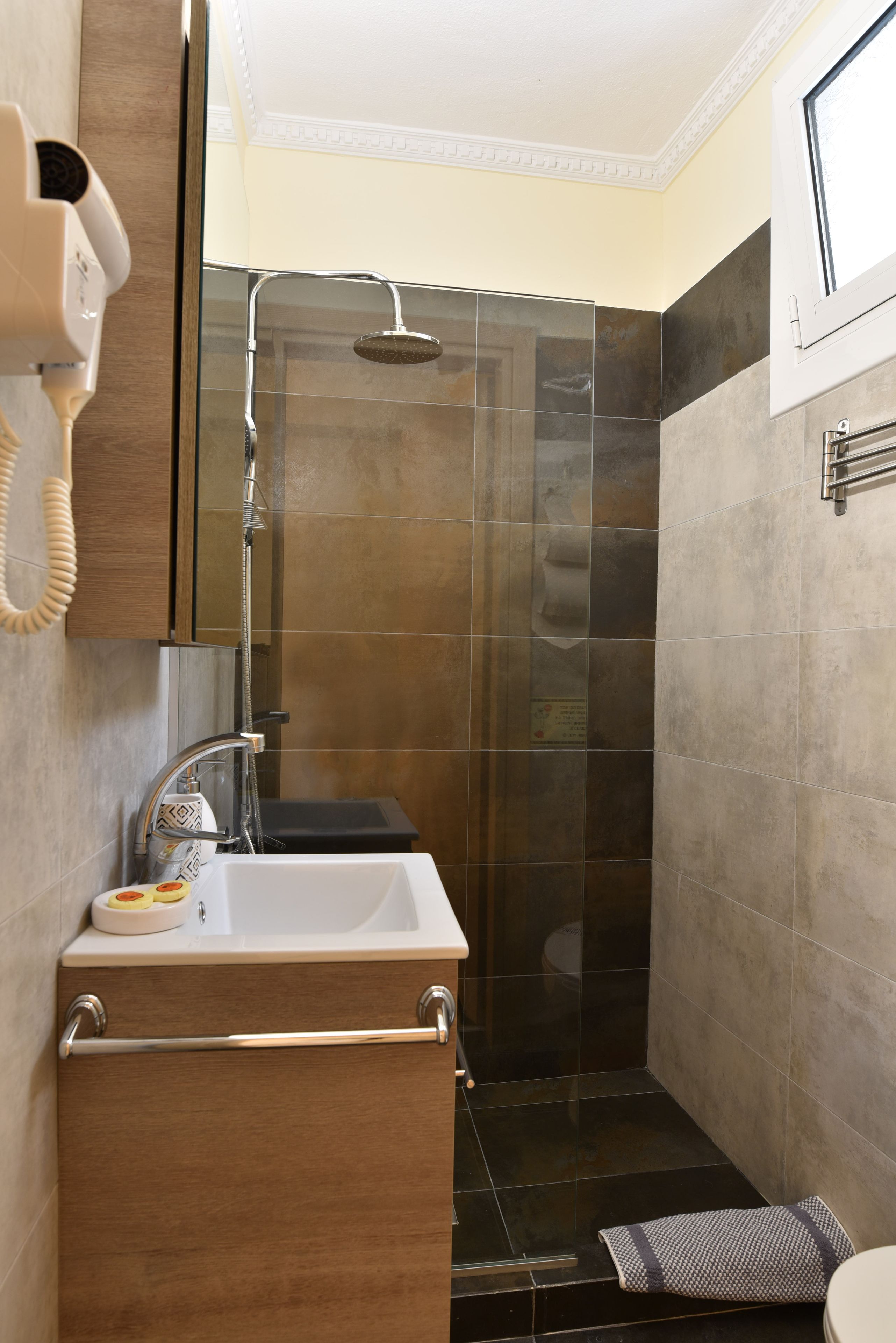 Ein modernes Badezimmer mit einer Glaskabine zur Dusche, einem Waschbecken mit Seifenschale und einem Handtuchhalter.