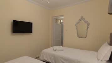 A hotel room with two beds, a flat-screen TV, a decorative mirror, and a chandelier.