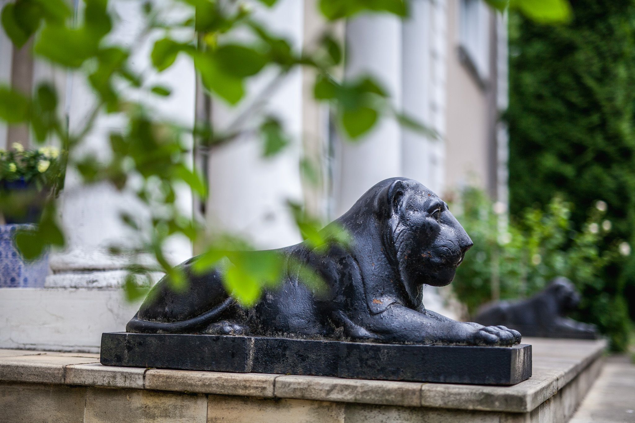A statue of a reclining lion in a garden setting.