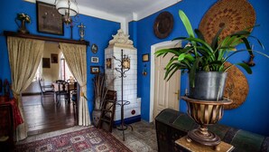 A room with blue walls, a white fireplace, and a wooden floor. There is a dining table with chairs and a hanging light fixture. - Dwor W Odonowie (Kazimierza Wielka)