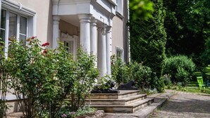 A stately building with a grand entrance, a well-maintained garden, and a cobblestone pathway leading to the entrance. - Dwor W Odonowie (Kazimierza Wielka)