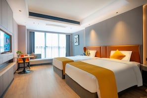 Habitación de hotel con dos camas, zona de estar, televisor y vistas desde el balcón.