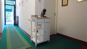 Un couloir avec un chariot blanc, un tapis vert et des tableaux encadrés accrochés aux murs.