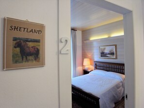 A hotel room with a bed, a nightstand with a lamp, a framed picture on the wall, and a sign with the name 'Shetland'. - Società Agricola La Staccionata (Staranzano)