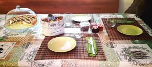 Una mesa de comedor dispuesta con platos, cubiertos y un pastel sobre un mantel estampado.