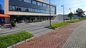 A modern building with a flat roof, large windows, and a paved entrance area with a brick pathway. - Hotel Ba Antowo Sport (Katowice)