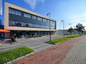 A modern building with a flat roof, large windows, and a paved entrance area with a brick pathway. - Hotel Ba Antowo Sport (Katowice)