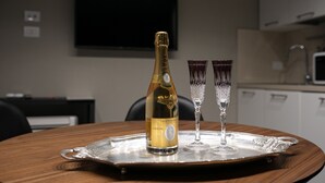 Una botella de champán Cristal y dos copas de cristal sobre una bandeja de plata en una mesa de madera.