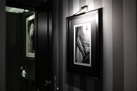A framed photograph on a wall, a door with a handle, and a small table with a vase.