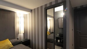 Una habitación de hotel con cama, mesita de noche, espejo y puerta.