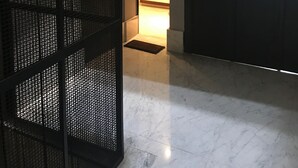 Un pasillo con una partición de metal negro, una puerta de cristal y una escalera que lleva a otra habitación.