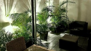 Una habitación con una mesa de comedor, sillas, un sofá y plantas en macetas.