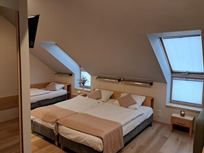 A bedroom with two beds, a skylight, and a small bedside table with a lamp. - Hotel Kolna (Kraków)