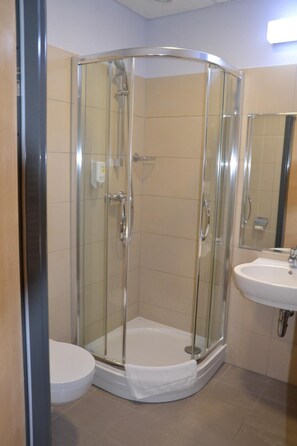 A glass-enclosed shower stall with a white toilet and sink. - Hotel Kolna (Kraków)