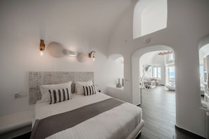 Een moderne slaapkamer met een groot bed, een hoofdeinde met een patroon en een uitzicht op een eetruimte via een boog.