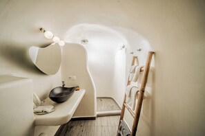 Un baño con lavamanos curvo, un espejo y ducha.