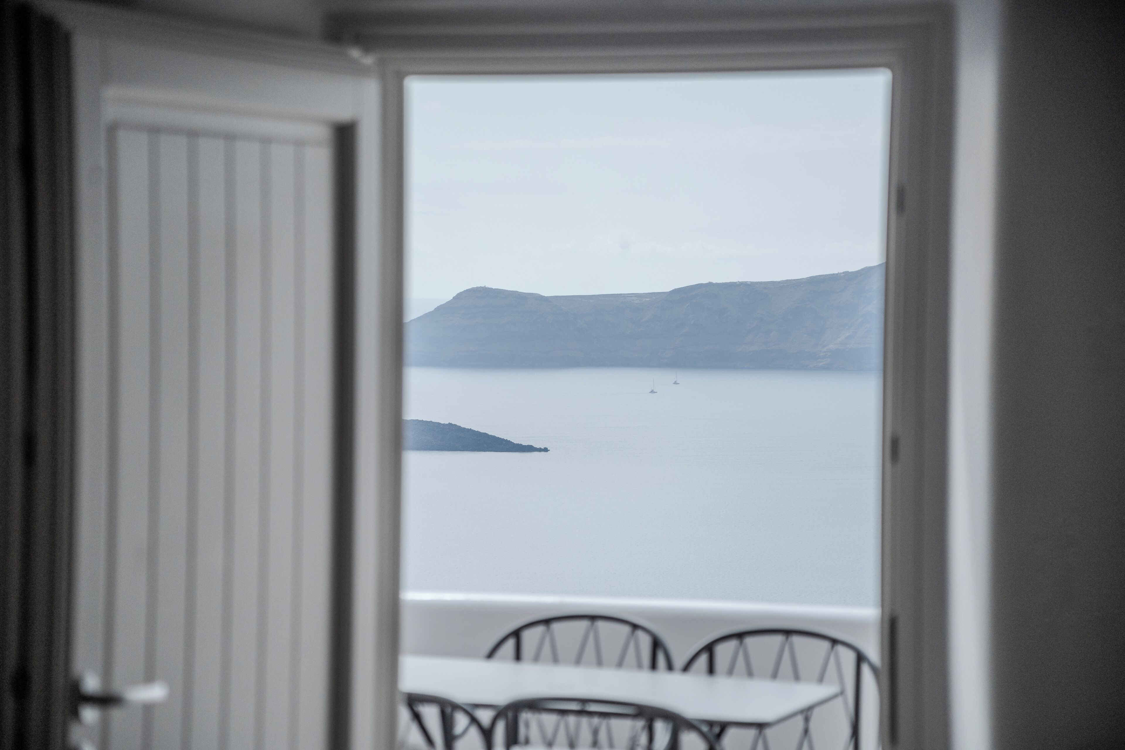 Habitación con vista a una masa de agua tranquila y formas de relieve a lo lejos, a través de una puerta abierta.