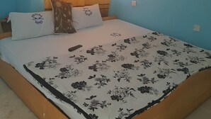 Una cama con una colcha estampada, una almohada con un logo y un control remoto encima.