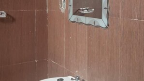 Un baño con lavamanos blanco, un espejo y azulejos marrones.