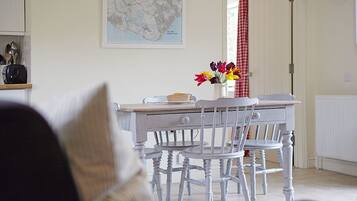 A dining area with a white table and chairs, a map on the wall, and a vase with flowers.