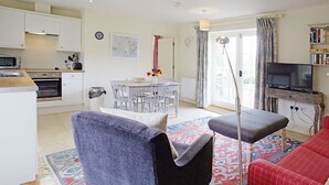 A compact living space with a kitchenette, dining area, and seating area. - Fig Cottage (Eastbourne)