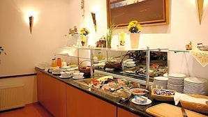 A buffet setup with various food items and a flower arrangement on the counter.