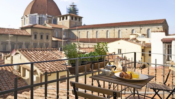 Ein Balkon mit Frühstückstisch, Blick auf ein historisches Gebäude mit Kuppel und Glockenturm.