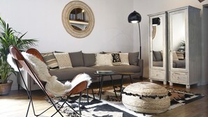 Ein modernes Wohnzimmer mit einem Sofa, einem Sessel, einem runden Spiegel und einer Stehlampe.