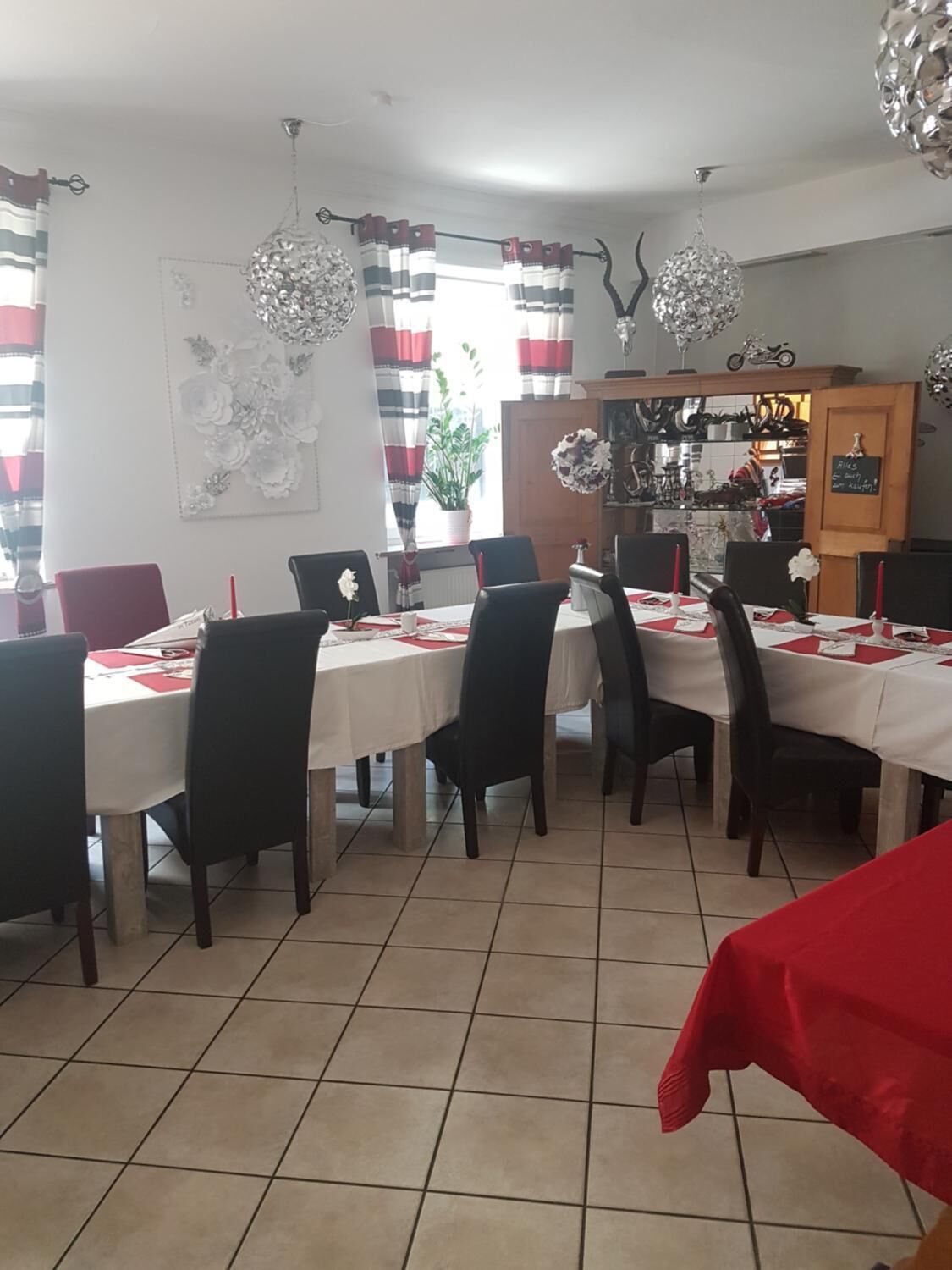 A dining area with a tiled floor, white tablecloths, and black chairs.