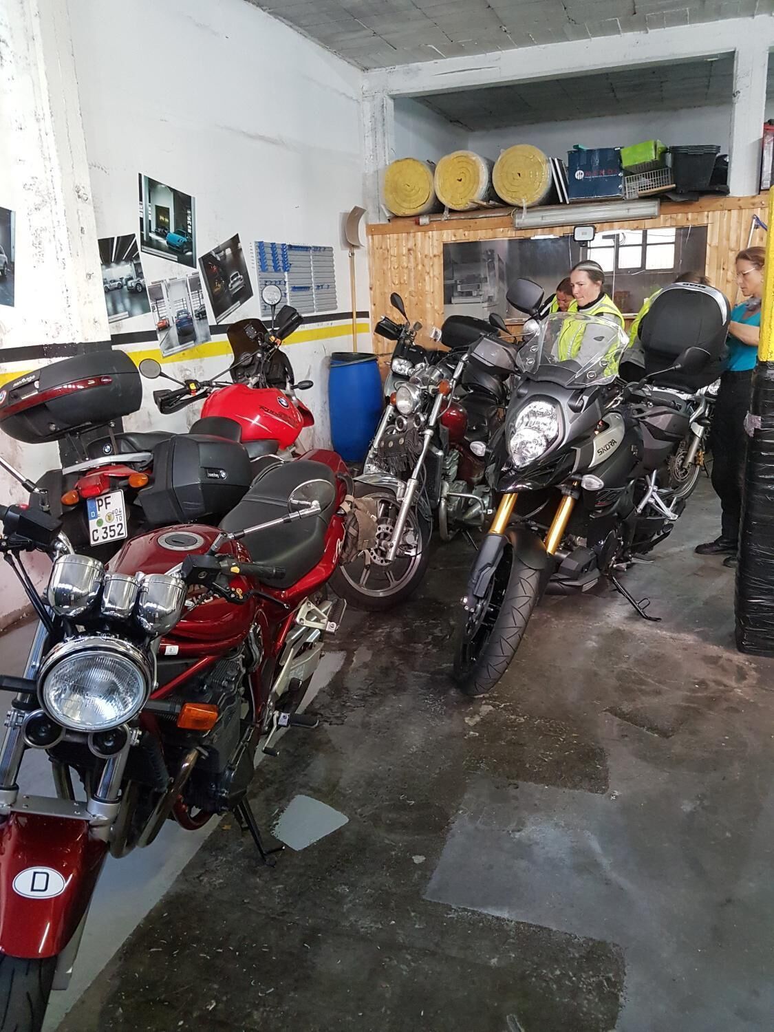 Un taller de reparación de motocicletas con varias motocicletas estacionadas, un banco de trabajo y herramientas.