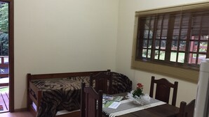 Ein kleines Zimmer mit einem Bett, einem Tisch und einem Fenster mit Jalousien.
