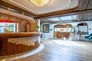 Un hall d’hôtel comprenant un comptoir d’accueil, un tableau et un espace repas.
