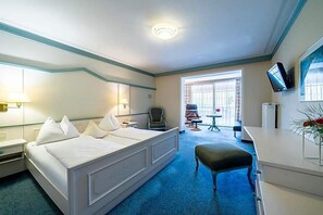 Une chambre d’hôtel avec un lit, un bureau, une chaise, une télévision et une fenêtre.