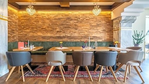 Un restaurante con pared de madera, asientos acolchados verdes y una lámpara de araña.