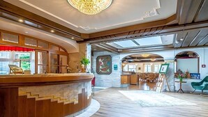 Un vestíbulo de hotel con una recepción, un cuadro y un área de comedor.