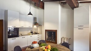 Een moderne keuken met witte kasten, een inbouwoven en een eethoek met een houten tafel gedekt voor een maaltijd.