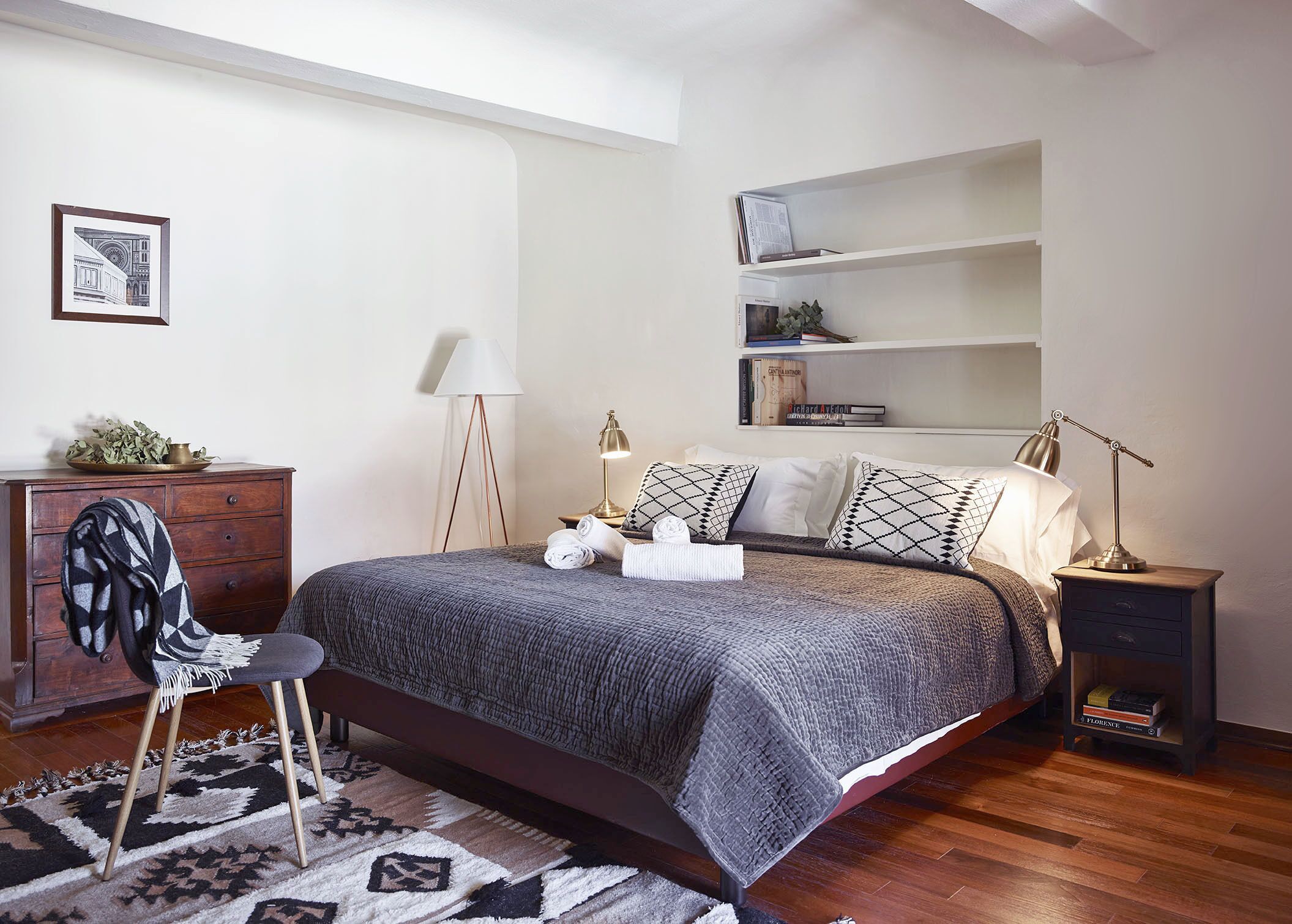 Une chambre à coucher comprenant un lit, des tables de chevet, une chaise, une commode et une bibliothèque.