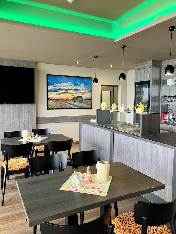 A modern dining area with a central island, black chairs, and a large painting on the wall. - Hotel Seeblick Garni (Gartow)