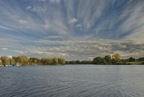 A calm lake with boats, trees, and houses in the background. - Hotel Seeblick Garni (Gartow)