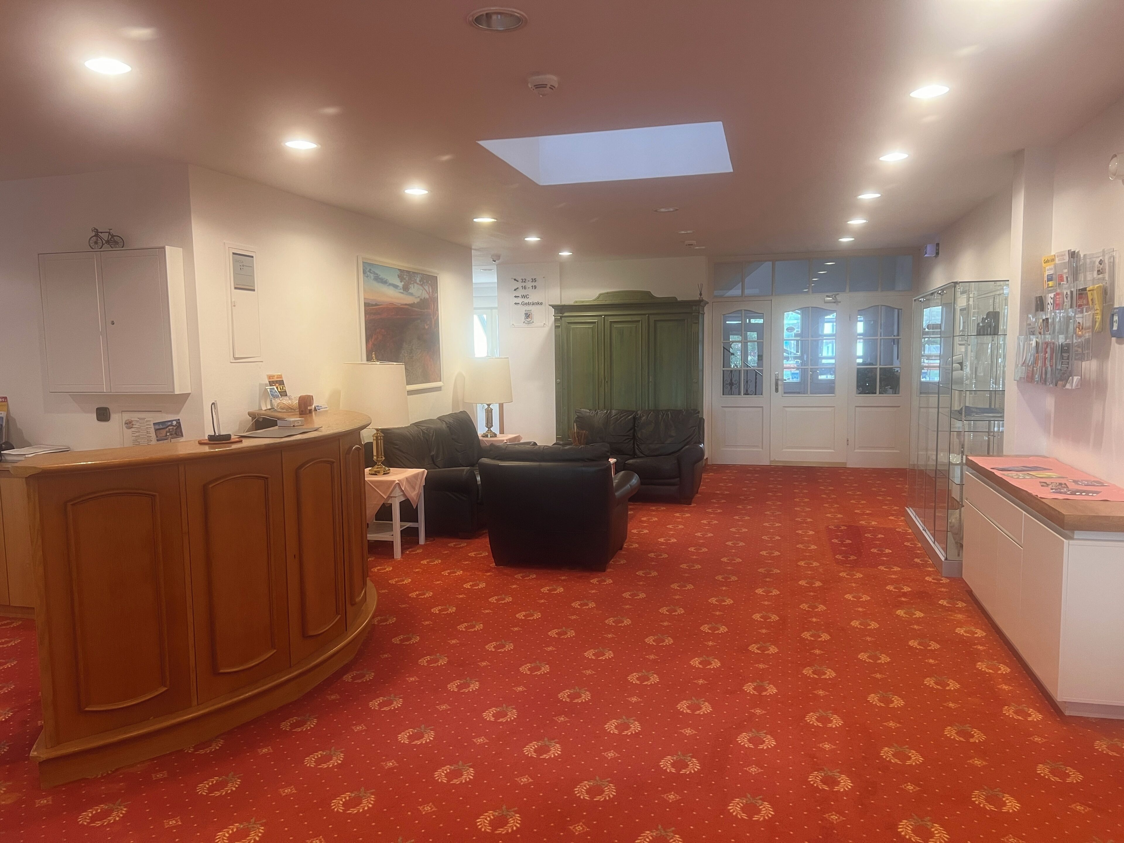 Eine Hotelhalle mit Empfangstresen, Sitzgelegenheiten und einer Glastausche.'
